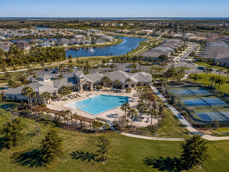 Aerial view of a planned Florida community with homes, pools, tropical landscaping, and internal walking paths